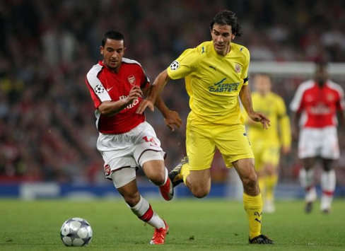 Theo Walcott tussles with former Arsenal star Robert Pires during the Champions League quarter-final second leg at the Emirates