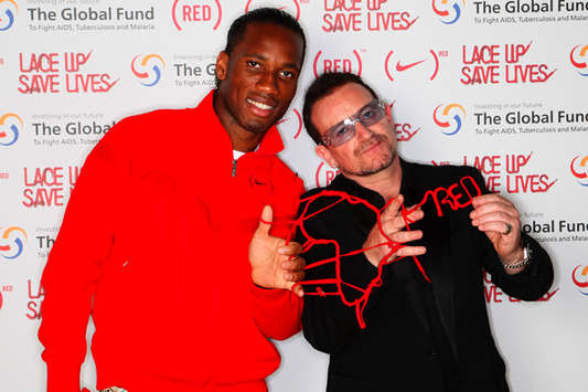 Didier Drogba dan Bono U2 menunjukkan kepedulian mereka terhadap isu global HIV/AIDS dengan mendukung penuh kampanye "Lace Up Save Lives" bersama Nike dan [RED] - (GOAL.com / Nike)